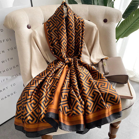 Orange and black patterned scarf draped over a beige armchair with a small bag beside it.