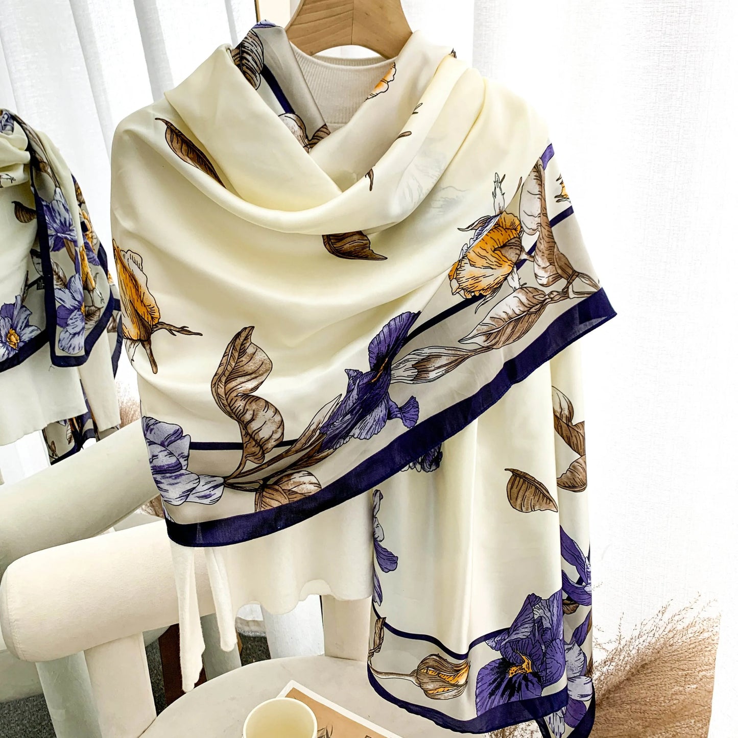 Luxury cream silk-feel satin scarf with purple and gold botanical floral print draped gracefully.