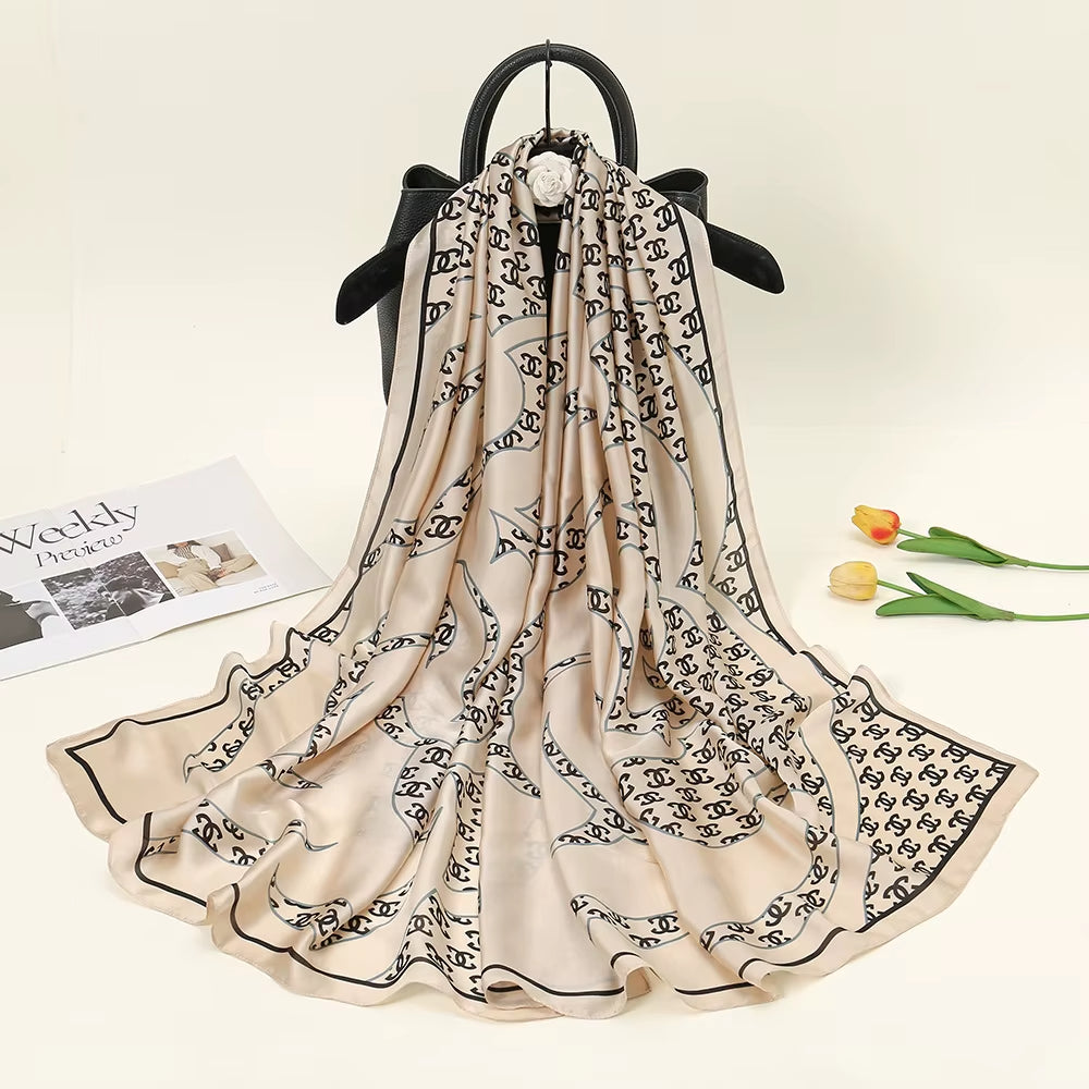 Experience timeless elegance with this luxurious silk-feel satin scarf. Features a chic cream and black monogram arranged in a sophisticated chain pattern. Measures 90 x 180 cm. The perfect accessory for any occasion.
