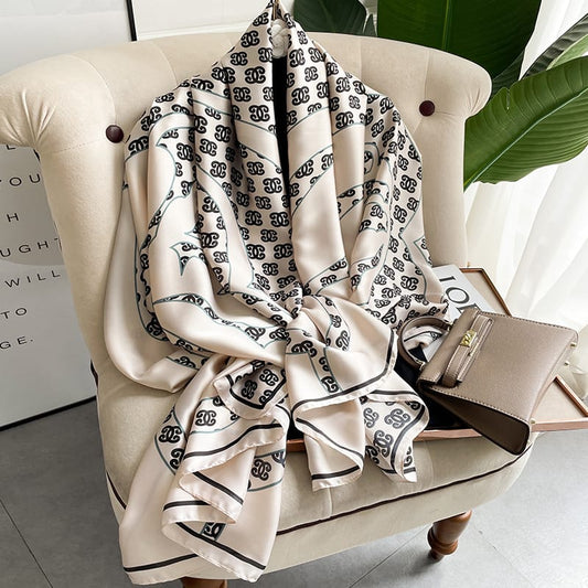 Experience timeless elegance with this luxurious silk-feel satin scarf. Features a chic cream and black monogram arranged in a sophisticated chain pattern. Measures 90 x 180 cm. The perfect accessory for any occasion.