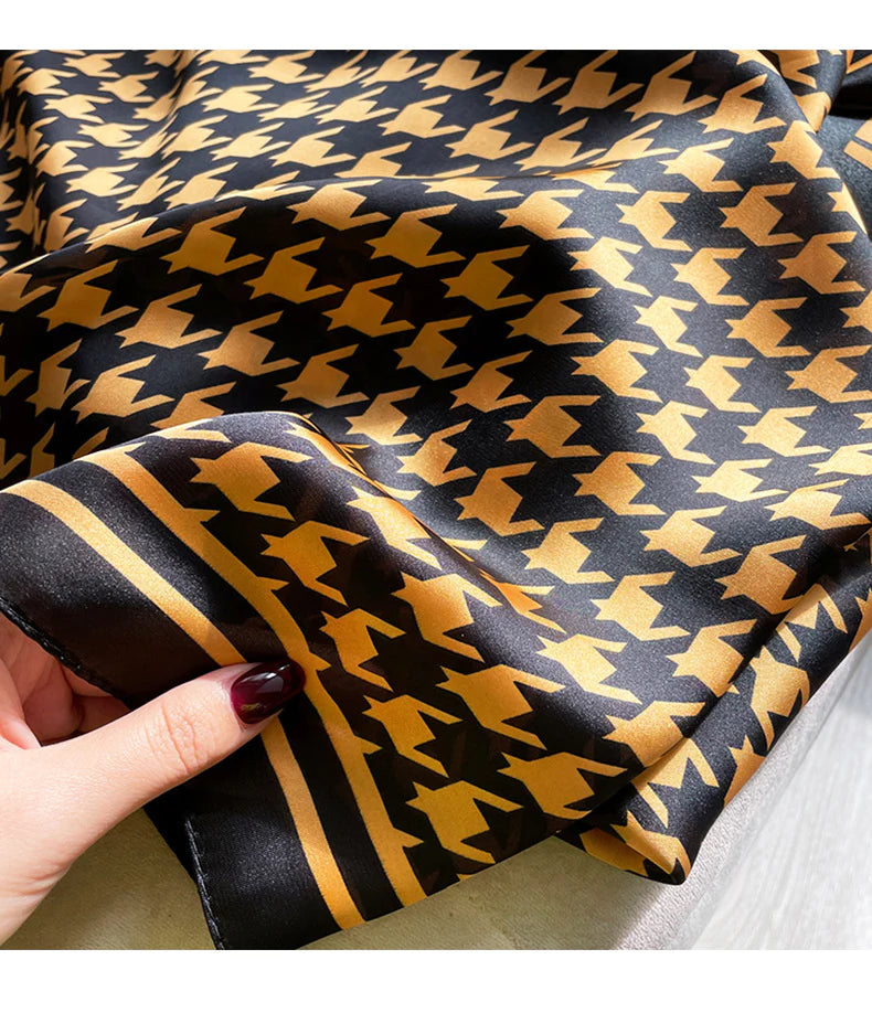 Elevate your wardrobe with this luxurious silk-feel satin scarf. Featuring a timeless gold and black houndstooth pattern complemented by a modern monogram border, this 90 x 180 cm scarf is the definition of chic.