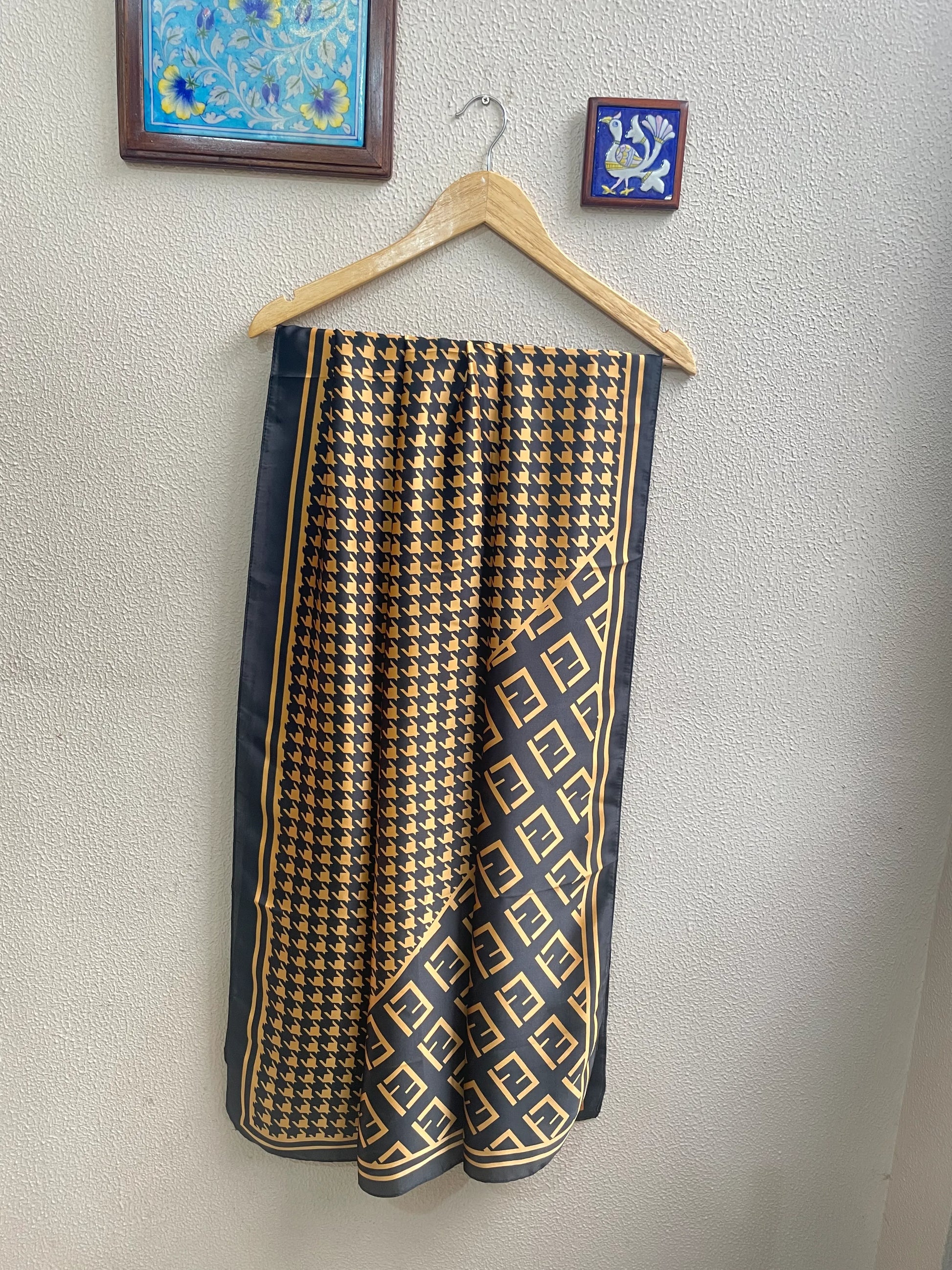 Elevate your wardrobe with this luxurious silk-feel satin scarf. Featuring a timeless gold and black houndstooth pattern complemented by a modern monogram border, this 90 x 180 cm scarf is the definition of chic.