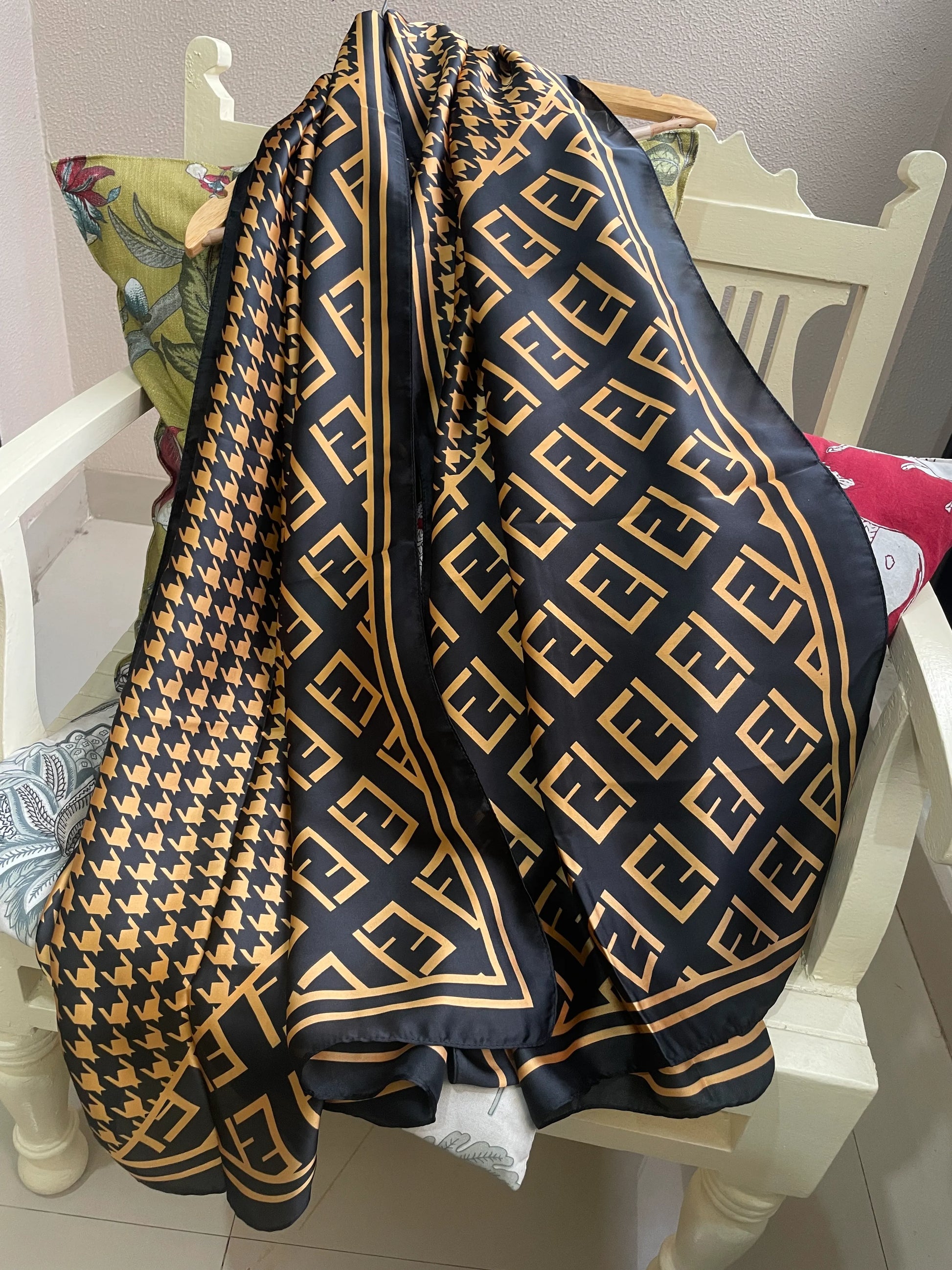 Elevate your wardrobe with this luxurious silk-feel satin scarf. Featuring a timeless gold and black houndstooth pattern complemented by a modern monogram border, this 90 x 180 cm scarf is the definition of chic.