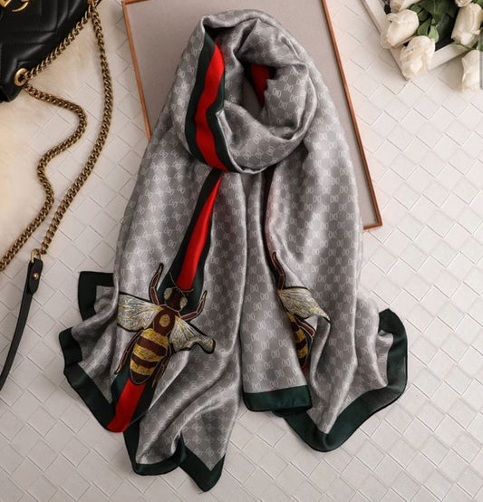 Elevate your style with this luxurious silk-feel satin scarf in light grey monogram with a bold red and green stripe and charming bee motif. Measuring 90 x 180 cm, it’s perfect for evening wear, travel, or as a sophisticated gift.