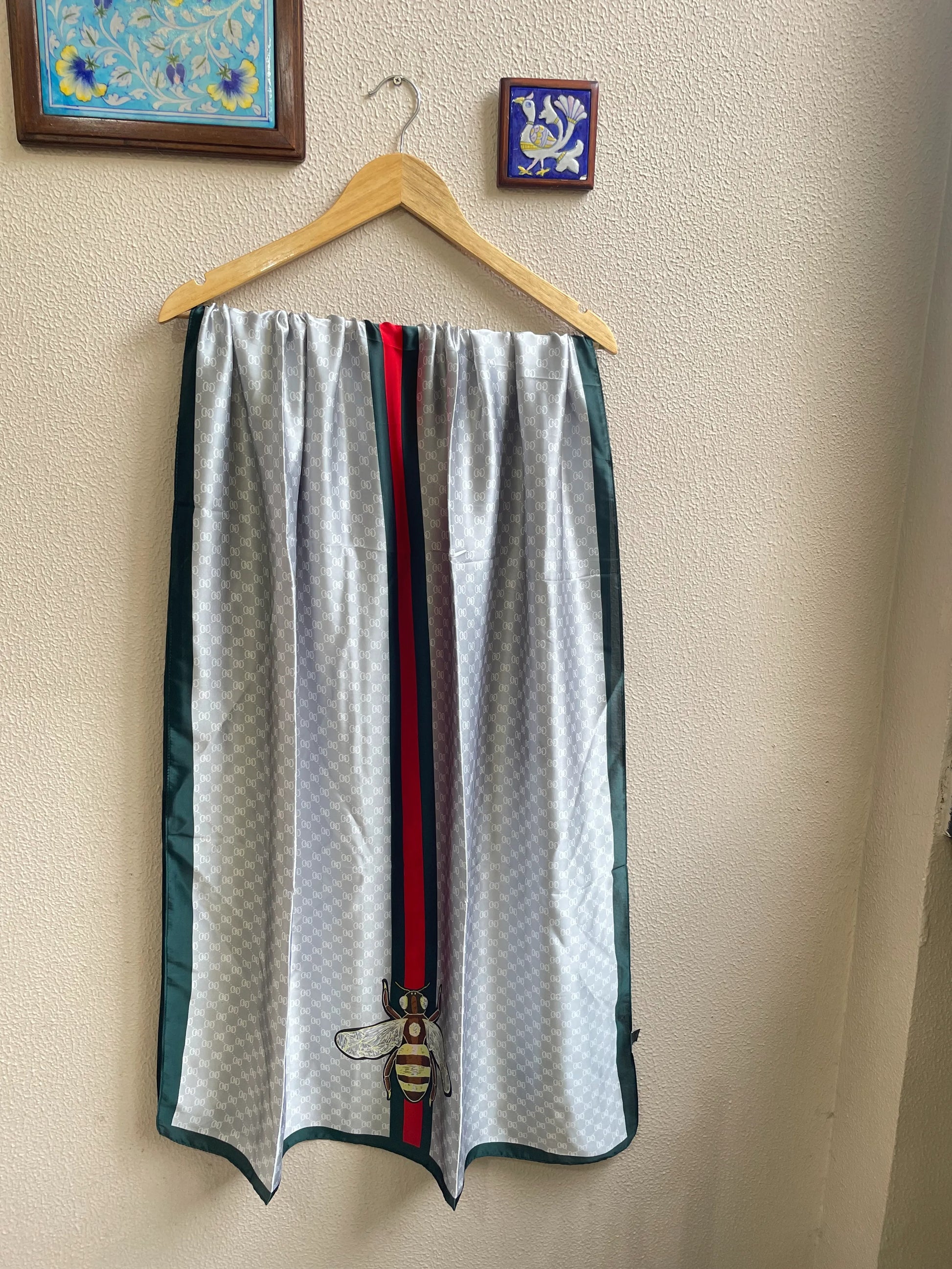 Elevate your style with this luxurious silk-feel satin scarf in light grey monogram with a bold red and green stripe and charming bee motif. Measuring 90 x 180 cm, it’s perfect for evening wear, travel, or as a sophisticated gift.
