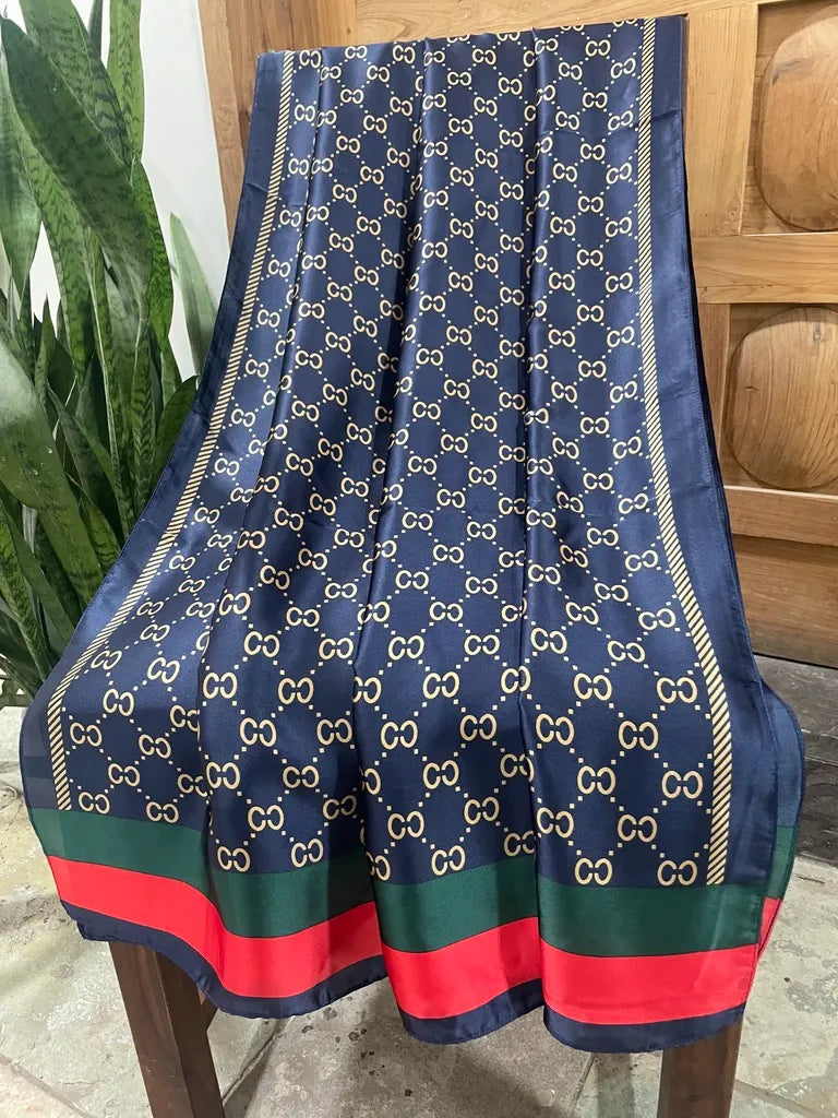 Elevate your style with this luxurious silk-feel satin scarf. Features a deep navy and gold monogram design with iconic red and green stripes. Size 90 x 180 cm.
