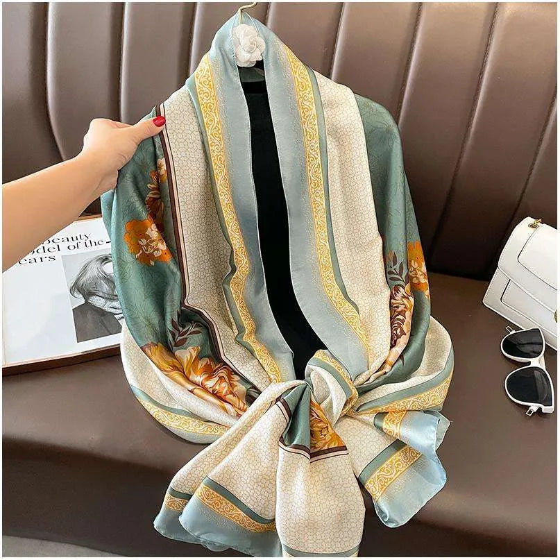 Full view of a sage green satin scarf featuring large amber flowers and detailed cream borders.