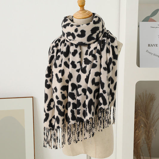 Leopard print scarf with tassels on a mannequin against a white wall.
