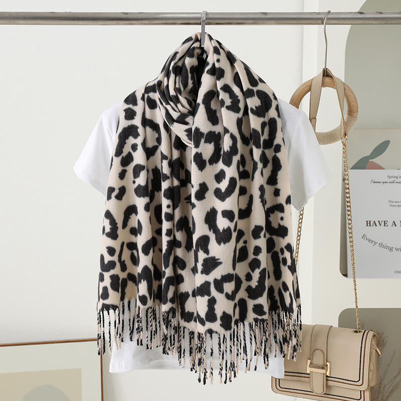 Leopard print scarf draped over a white shirt with a beige handbag in the background.