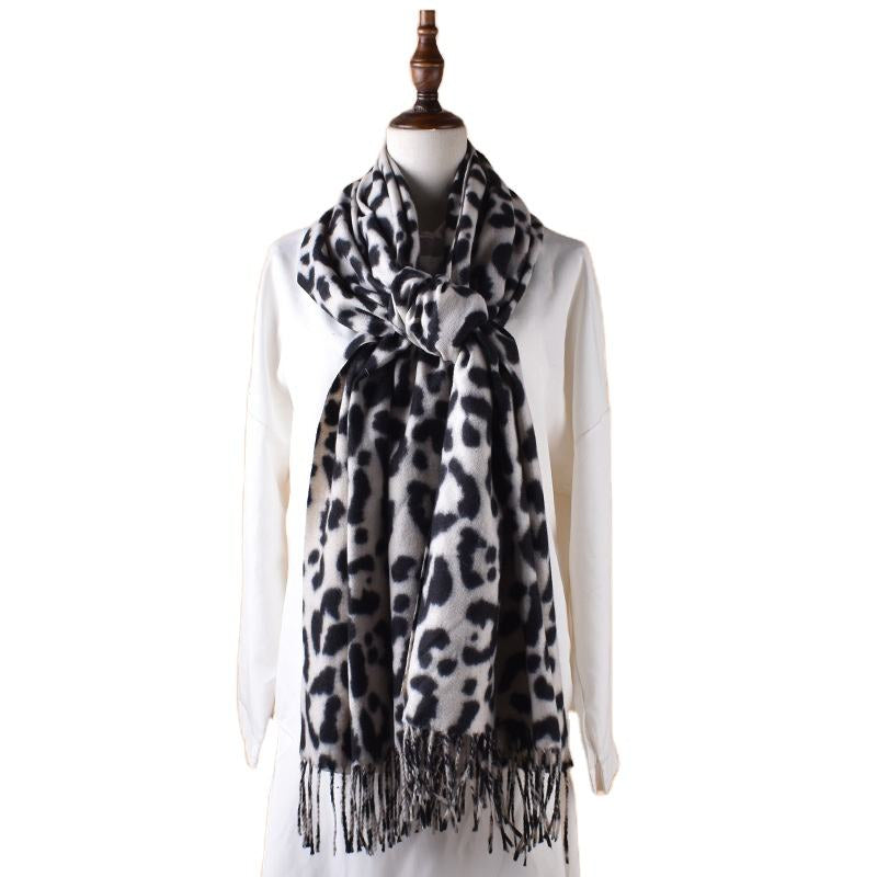 Leopard print scarf with tassels on a mannequin against a white background
