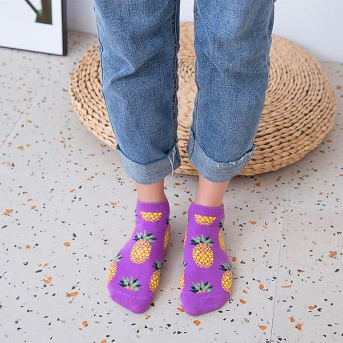 Purple socks with a funky pineapple pattern worn by a person on a speckled floor.
