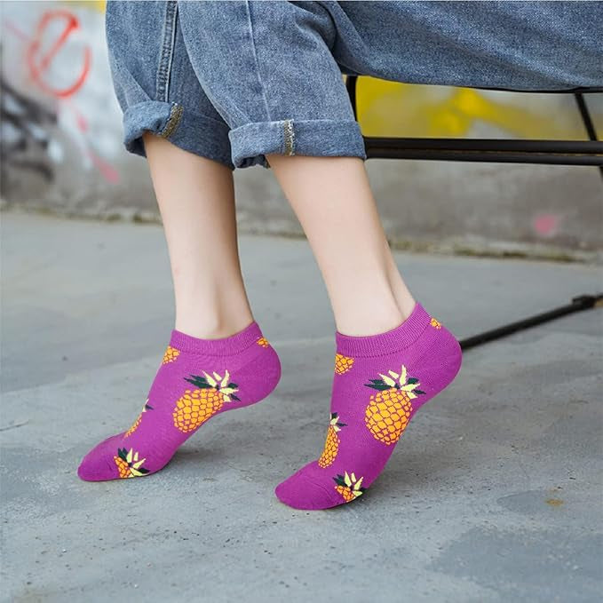 Purple socks with pineapple design worn by a person on a concrete surface.