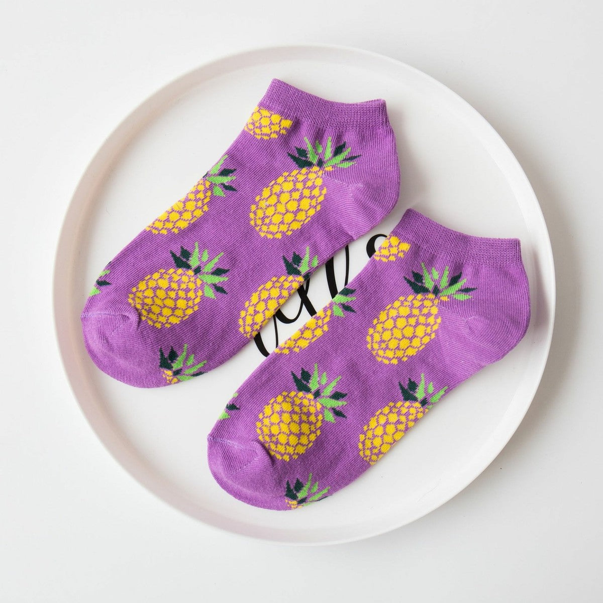 Funly purple socks with pineapple pattern on a white plate