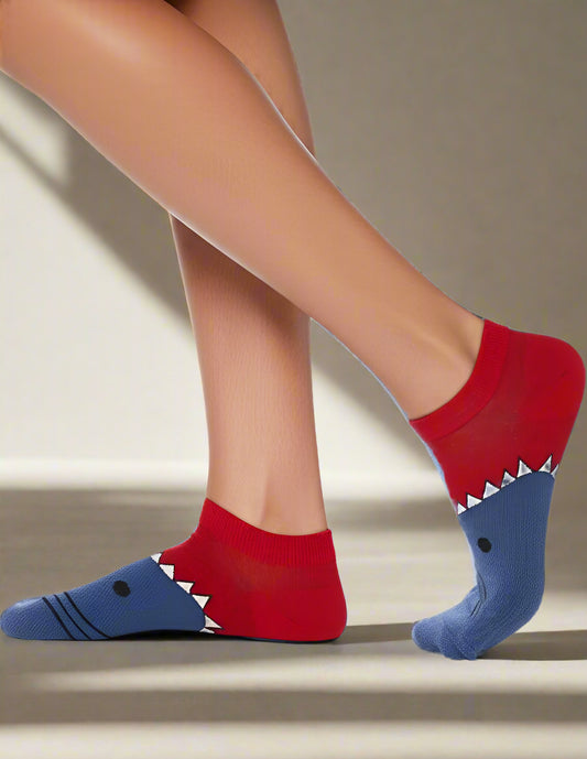 Red and blue shark-themed socks worn by a person on a light gray background