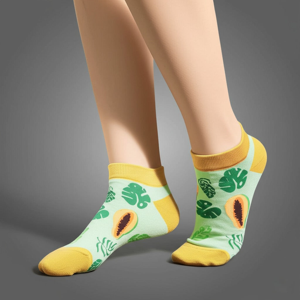 Green socks with tropical leaf and papaya design worn by a person on a gray background