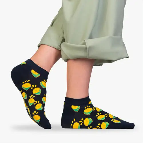 Person wearing black socks with  yellow lemon pattern 