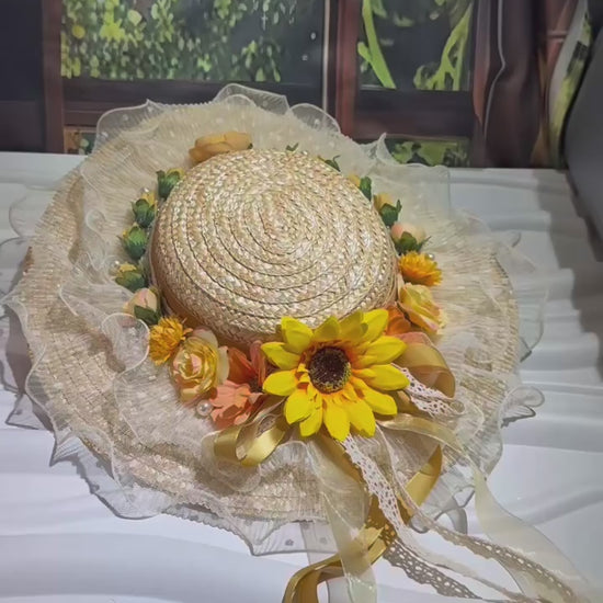 Embrace countryside charm with our Marisol sunflower straw hat. This vintage-inspired boater features a ruffled lace brim, pearl accents, and flowing yellow ribbons. Perfect for summer events.