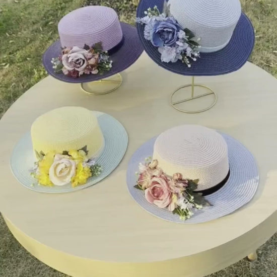 Vintage floral boater hat made of papyrus with l flowers and ribbon, displayed on wicker basket with garden-themed decor.