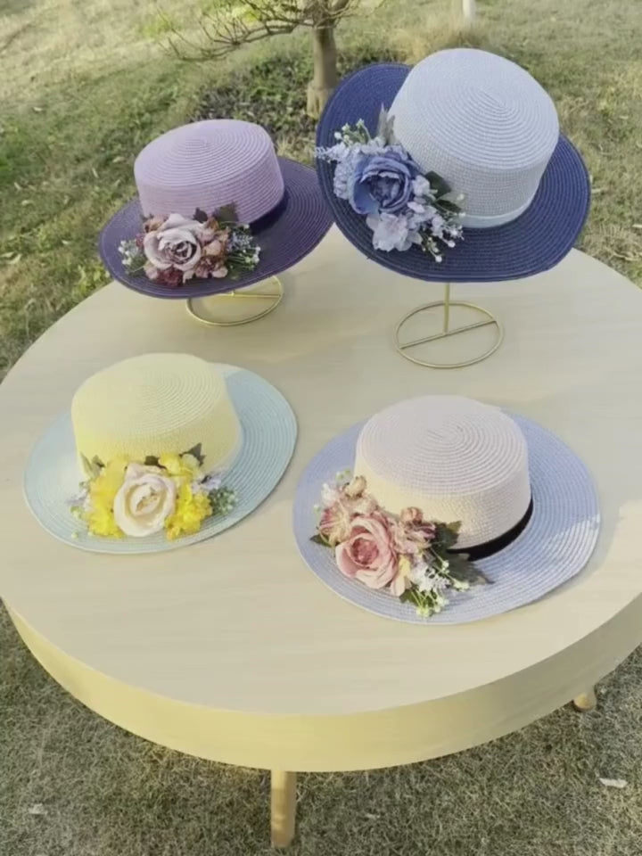 Vintage floral boater hat made of papyrus with l flowers and ribbon, displayed on wicker basket with garden-themed decor.
